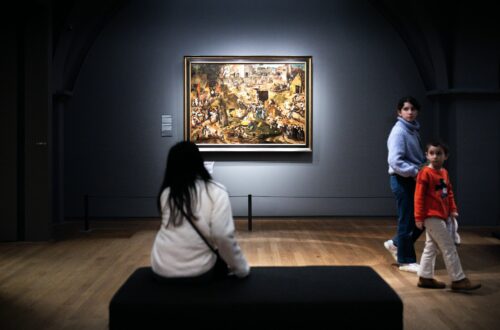 Mor og barn står sammen og kigger på et maleri på et kunstmuseum
